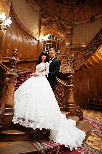 Casal incrível em grandes escadas de madeira no palácio rico . — Fotografia de Stock