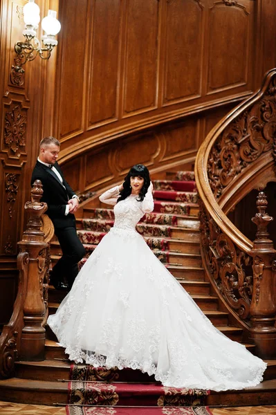 Casal incrível em grandes escadas de madeira no palácio rico . — Fotografia de Stock