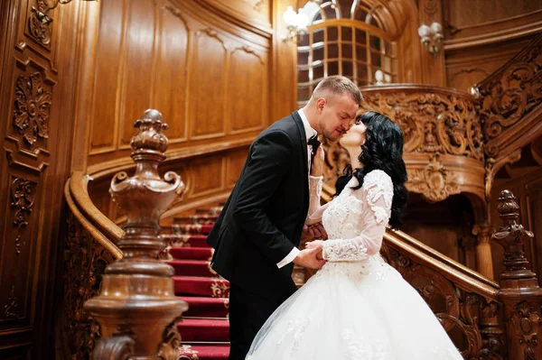 Geweldige bruidspaar op grote houten trappen in rijke palace. — Stockfoto