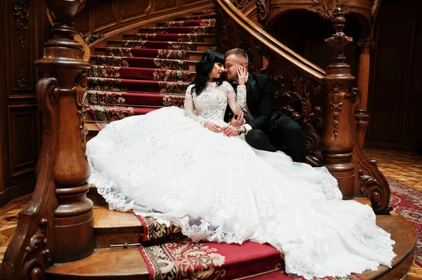 Casal de casamento encantador sentado em ricas escadas de madeira em grande r — Fotografia de Stock