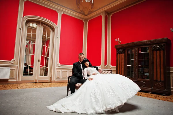 Стильна весільна пара на червоній кімнаті в палаці . — стокове фото