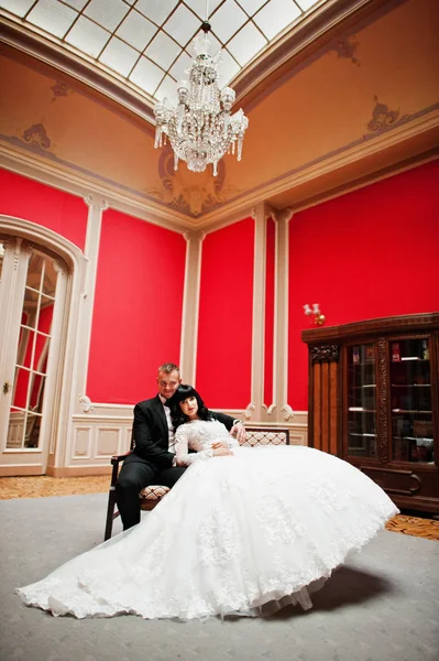 Stilvolles Hochzeitspaar auf rotem Zimmer im Palast. — Stockfoto