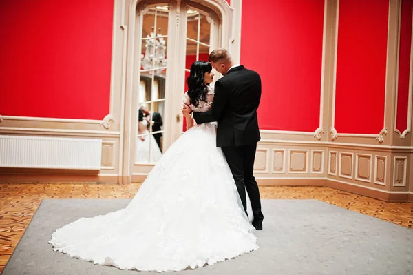 Stylish wedding couple on red room at palace. — Stock Photo, Image