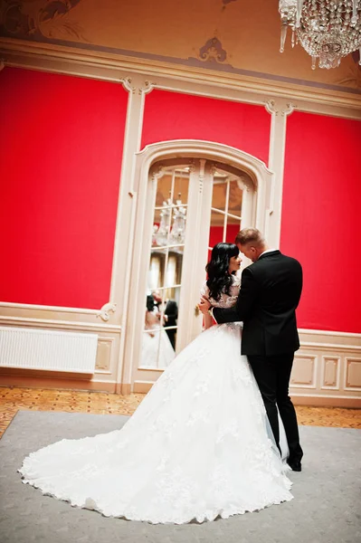 Stilvolles Hochzeitspaar auf rotem Zimmer im Palast. — Stockfoto