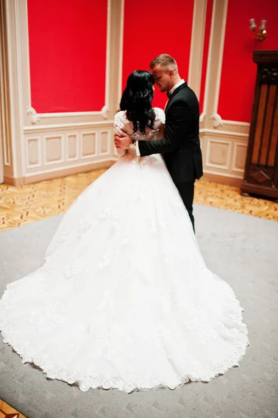 Stilvolles Hochzeitspaar auf rotem Zimmer im Palast. — Stockfoto