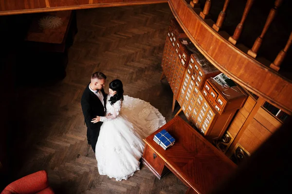 Bruidspaar op oude houten bibliotheek op hun trouwdag. — Stockfoto