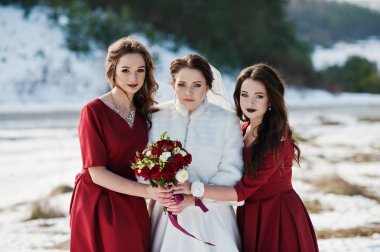 Kırmızı elbise üzerinde güzel nedime gelin güneşli kış ile evlenmek