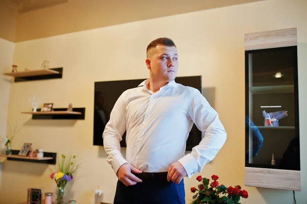 Young strong man wearing belt on his wedding day. Morning groom