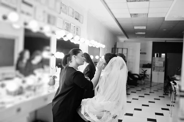 Make up artist doing professional makeup of young woman bride ne