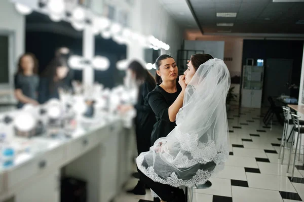 Make up artist facendo trucco professionale di giovane donna sposa ne — Foto Stock