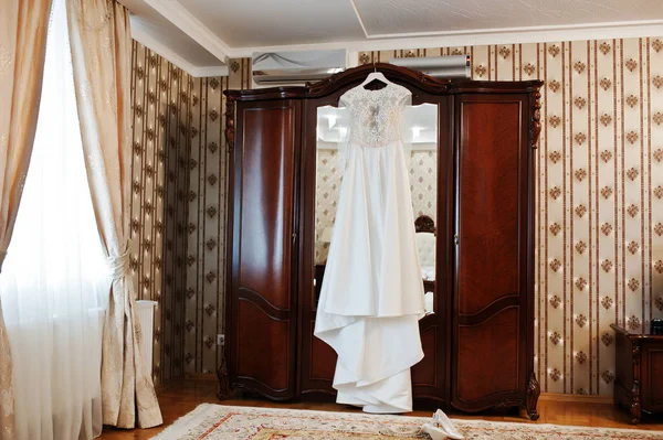 Amazing wedding dress on hangers at wooden closet on room of bri — Stock Photo, Image