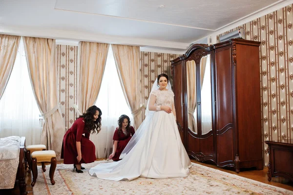 Два молодых и шикарных жениха в красном платье носят невесту на нем — стоковое фото