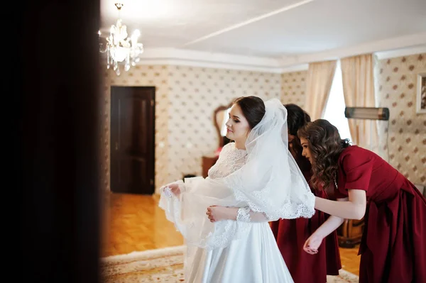 Zwei junge und hinreißende Brautjungfern auf rotem Kleid tragen Braut auf — Stockfoto