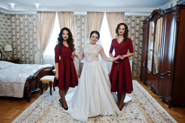 Noiva com duas damas de honra incríveis no vestido vermelho posado no quarto no — Fotografia de Stock