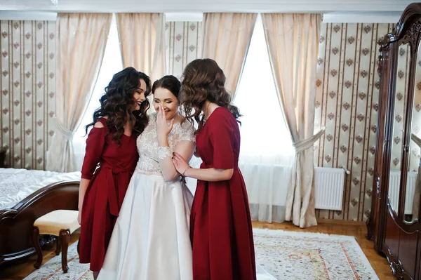 Sposa con due damigelle d'onore incredibili sul vestito rosso posato sulla stanza a — Foto Stock