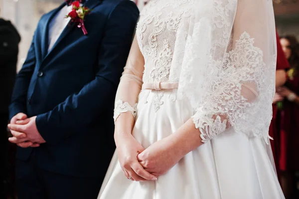 Handen van bruid en bruidegom op de ceremonie van het huwelijk in de kerk. — Stockfoto