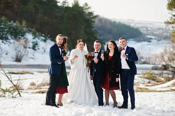 Best man with bridesmaids and newlyweds drinking champagne on fr