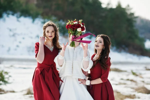 Hübsche Brautjungfern in roten Kleidern mit Braut im sonnigen Winter verheiratet — Stockfoto