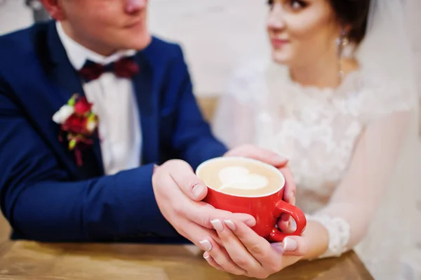 Newlyweds sitting on table at cafe with two cups of coffee — Stock Photo, Image