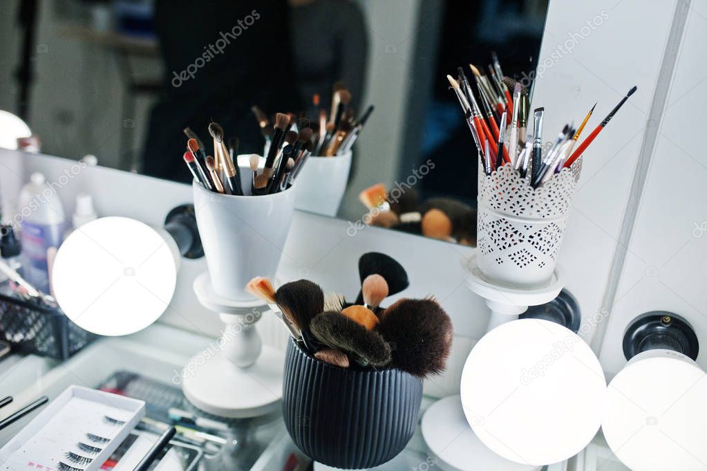 Various makeup brushes on table of beaty studio background mirro