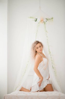 Bir beyaz ipek elbise boudoir Elbise yatakta içinde kıvırcık sarışın kız.