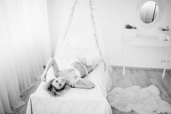 Krullend blond meisje in ondergoed liggend in bed binnen. — Stockfoto