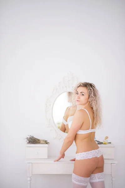 Curly menina loira em roupa interior fundo espelho interior branco ro — Fotografia de Stock