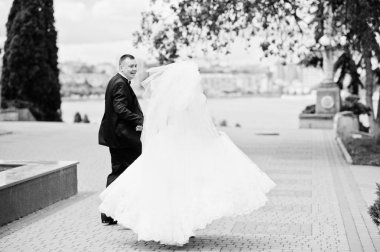 Tutuşup yürürken ve gülümseyen mutlu evlilik çift. Siyah bir