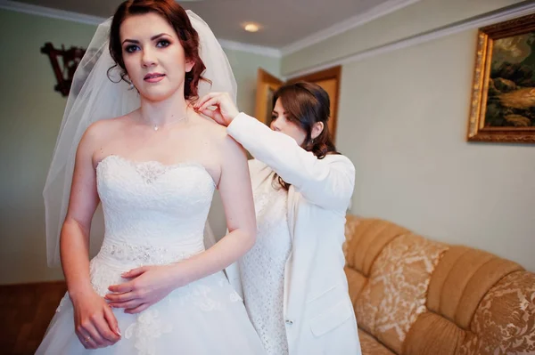 Подружки нареченої допомагають одягненій нареченій в день весілля вранці . — стокове фото