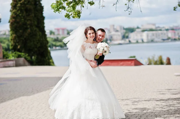 Esküvői pár átölelve háttér nagy város tó nevet. — Stock Fotó