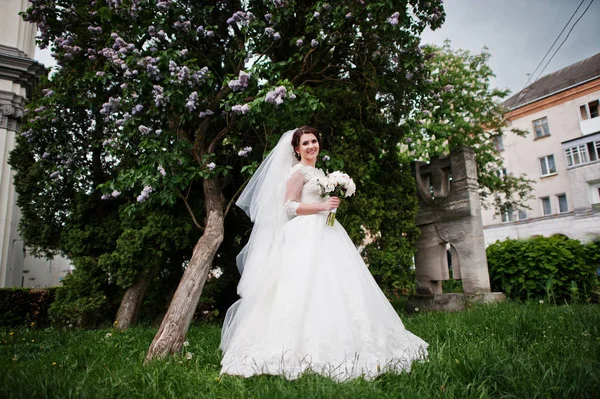 Cute brunette bride under lilac tree with wedding bouquet at han — Stock Photo, Image
