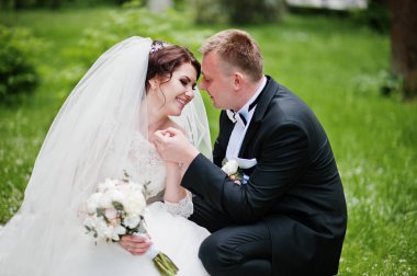 Yeşil çimenlerin üzerinde oturan ve birbirimizi Düğün çifti.