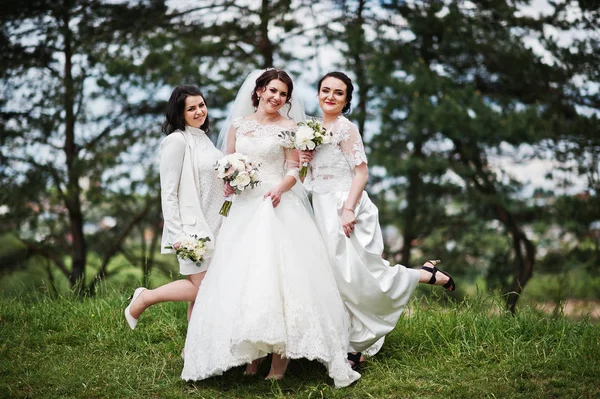 Hezká nevěsta s družičky na bílé šaty s kytice na — Stock fotografie