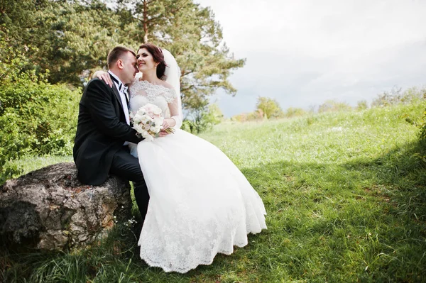 Büyük taş arka plan üzerinde güzel oturan güzel düğün Çift 