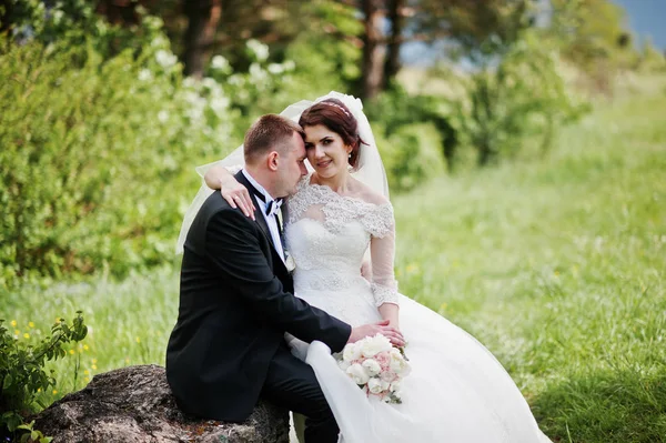 Bella coppia di nozze seduto su grande sfondo di pietra bella — Foto Stock