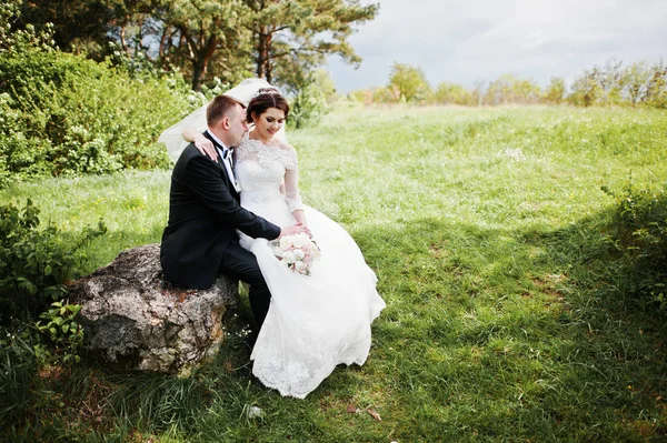 Lovely wedding couple sitting on big stone background beautiful — Stock Photo, Image