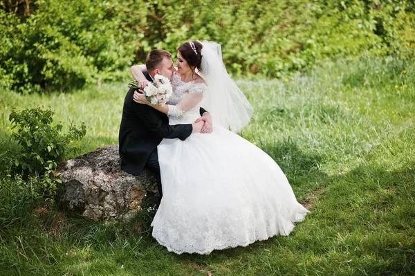 Hermosa pareja de boda sentada sobre un gran fondo de piedra hermosa —  Fotos de Stock