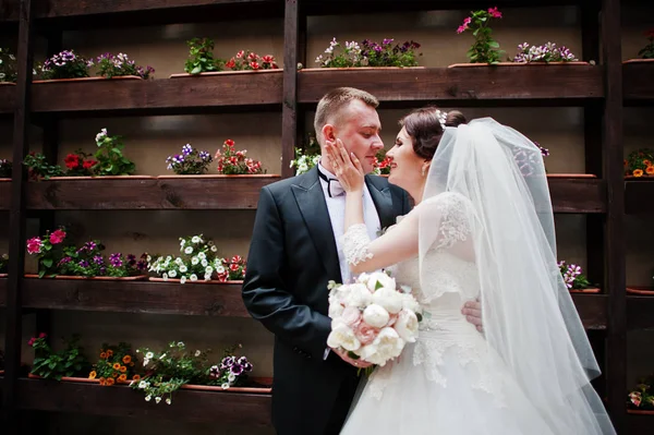 Krásné svatební pár zůstat pozadí zeď s květinami na po — Stock fotografie