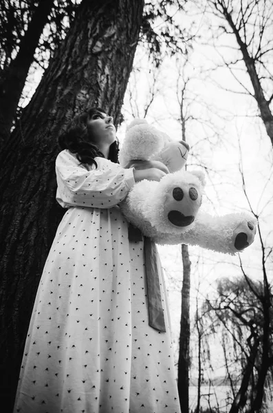 Genç üzücü yalnız esmer kıza pijama ile yumuşak oyuncak ayı o — Stok fotoğraf