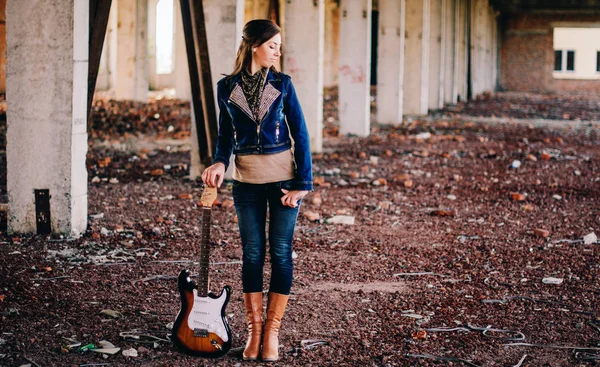 Giovane ragazza con una chitarra elettrica indossando giacca jeans su abadon — Foto Stock