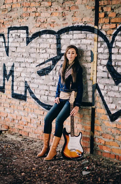 Giovane ragazza con una chitarra elettrica indossando giacca jeans su abadon — Foto Stock
