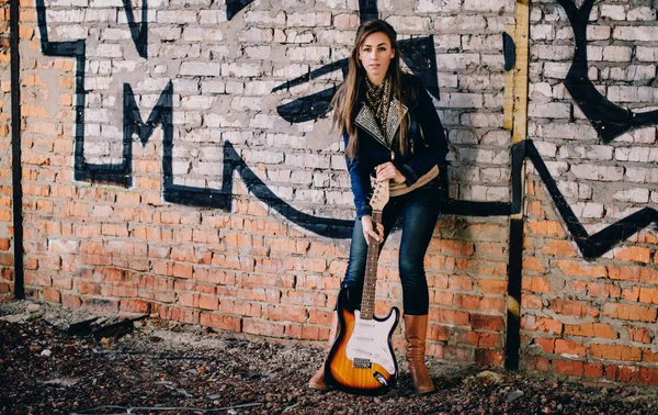 Giovane ragazza con una chitarra elettrica indossando giacca jeans su abadon — Foto Stock