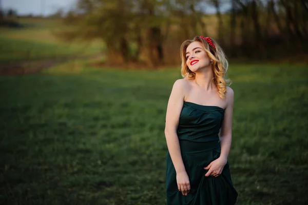 Весной блондинка в зеленом платье на огороде — стоковое фото
