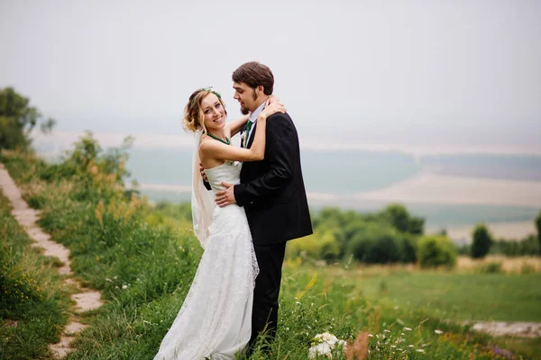 Embracing wedding couple in love on cloudy weather outdoor. — Stock Photo, Image