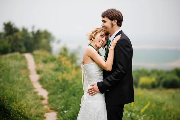 Abrazando pareja de boda en el amor en el tiempo nublado al aire libre . —  Fotos de Stock