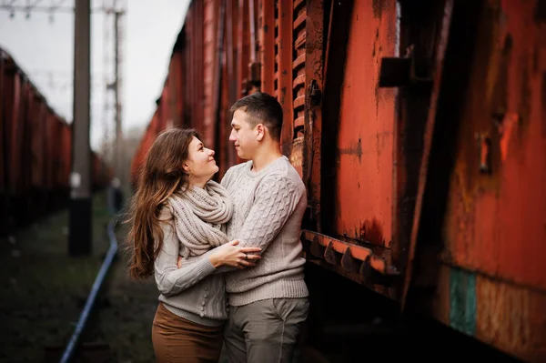 Jovem casal vestindo no amarrado quente suéteres abraçando no amor no ra — Fotografia de Stock