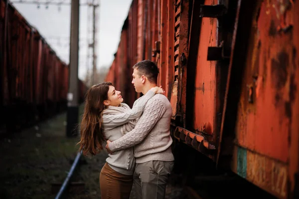 Jovem casal vestindo no amarrado quente suéteres abraçando no amor no ra — Fotografia de Stock