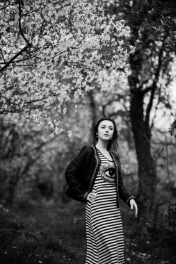 Esmer kız deri ceket, bahar bahçe üzerinde poz verdi. Siyah bir