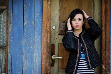 Esmer modeli kız deri ceket, arka plan eski woode poz verdi.