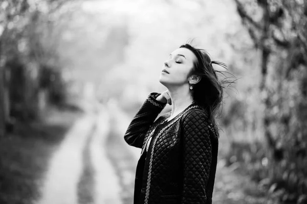 Menina morena em jaqueta de couro posou no jardim de primavera. Preto e... — Fotografia de Stock